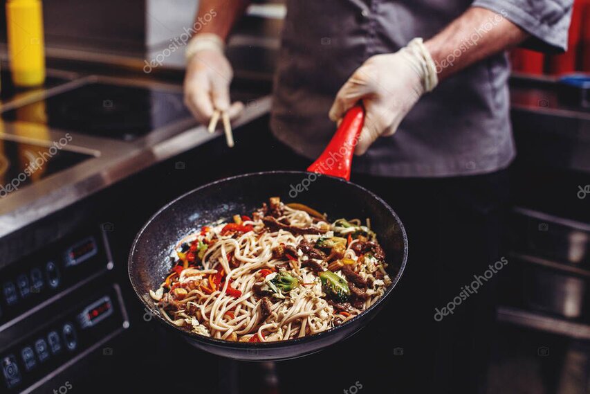 Farebné wok rezance so zeleninou a kúskami mäsa na tanieri